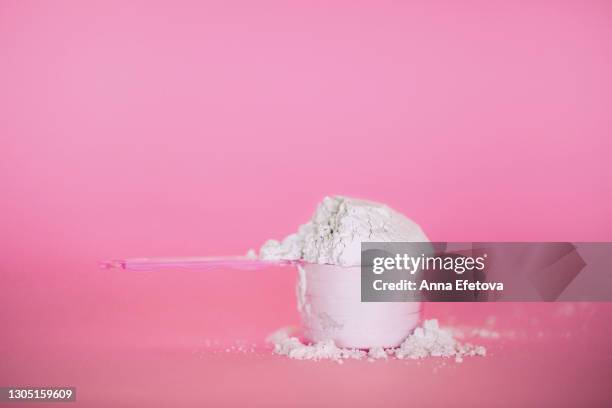measuring spoon with collagen powder or whey protein or alginate mask on pink background. trendy products of the year - powder foto e immagini stock
