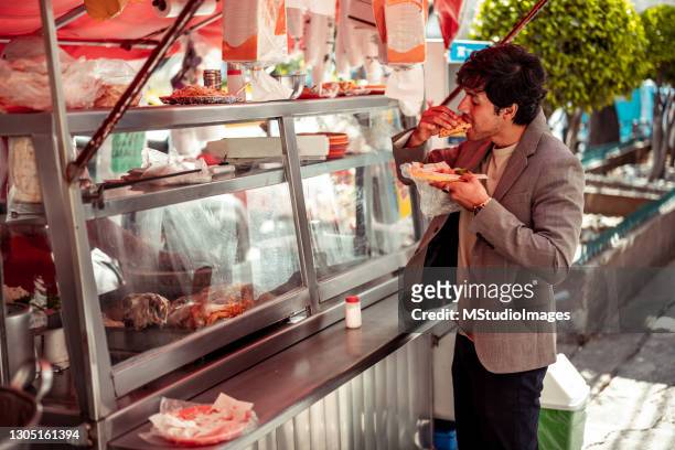young businessman garbing quick lunch - street food stock pictures, royalty-free photos & images