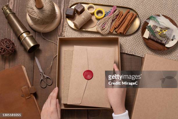woman's hand put a vintage letter envelope into gift box - gift lounge stock-fotos und bilder