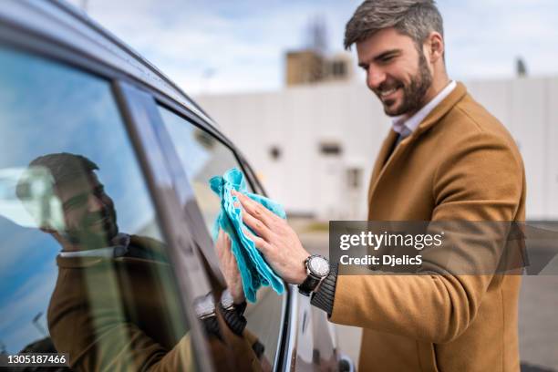 happy man cleaning his car's windows. - microfiber towel stock pictures, royalty-free photos & images