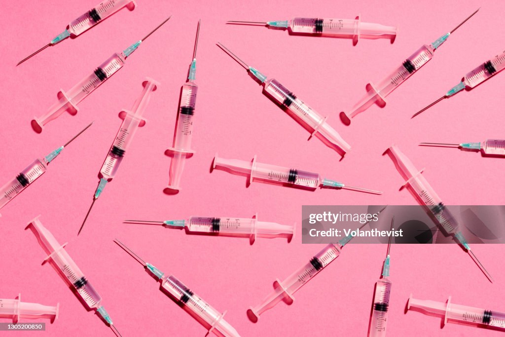 Syringe with injection or vaccine repetition pattern on pink background