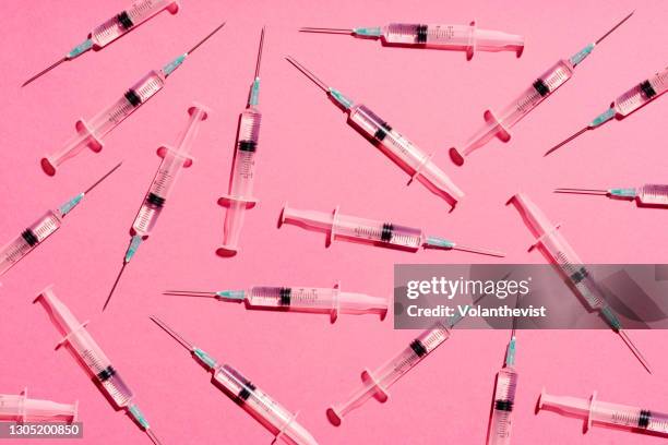 syringe with injection or vaccine repetition pattern on pink background - injecting stock pictures, royalty-free photos & images