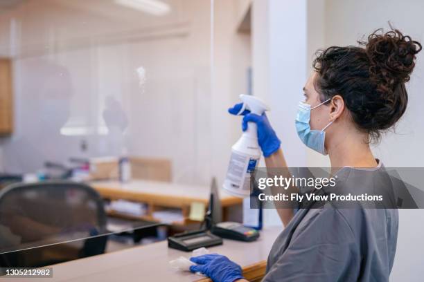 mixed race woman cleaning office front desk acrylic glass sneeze guard - disinfection stock pictures, royalty-free photos & images