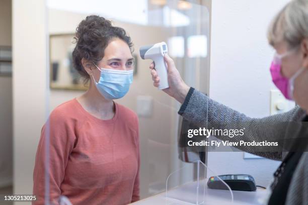 mixed race patient having temperature taken before medical appointment - hospital reopening stock pictures, royalty-free photos & images