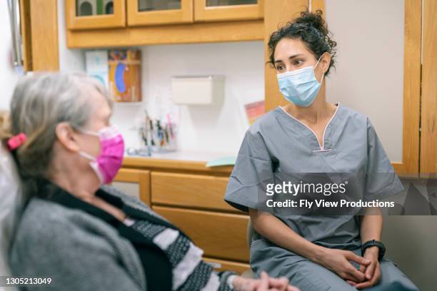 female medical professional consulting senior adult patient - eurasian female stock pictures, royalty-free photos & images