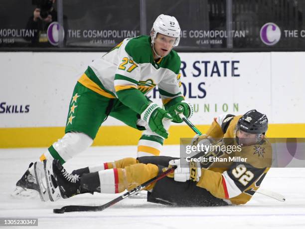 Tomas Nosek of the Vegas Golden Knights gets rid of the puck as he falls to the ice under pressure from Nick Bjugstad of the Minnesota Wild in the...