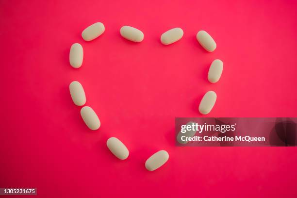 medicinal white prescription pills in shape of heart - statin stock pictures, royalty-free photos & images