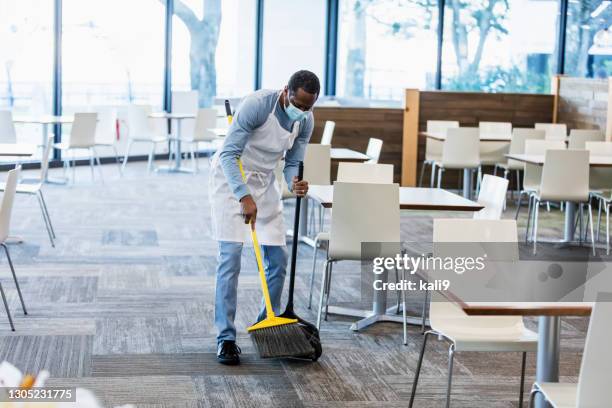 cafeteria worker sweeping floor, wearing mask - serviços de limpeza imagens e fotografias de stock