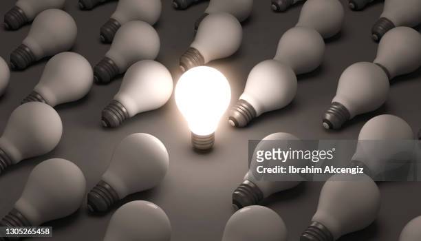 glowing light bulb standing out from the crowd - lightbulbs in a row stock pictures, royalty-free photos & images