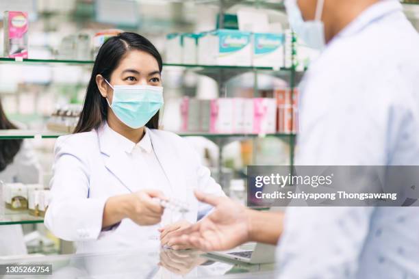 pharmacist advice medicine to young man in pharmaceutical store for healthcare and medicine concept. - pharmacy mask stock pictures, royalty-free photos & images