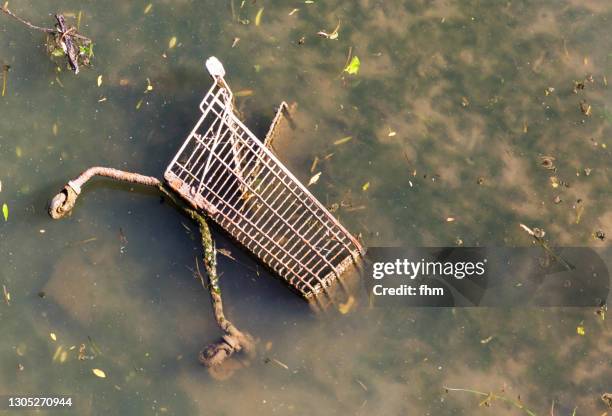 shopping caddy, thrown away in a dirty river - abandoned cart stock pictures, royalty-free photos & images