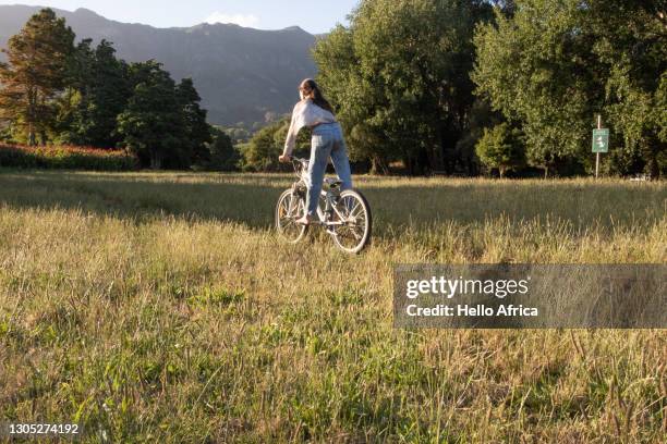 a teenager enjoying a peacful bicycle ride through a field. - bicycle stunt stock pictures, royalty-free photos & images