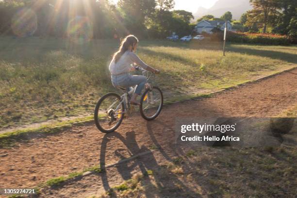 a young girl, riding her bicycle along a gravel path. - sketch foto e immagini stock