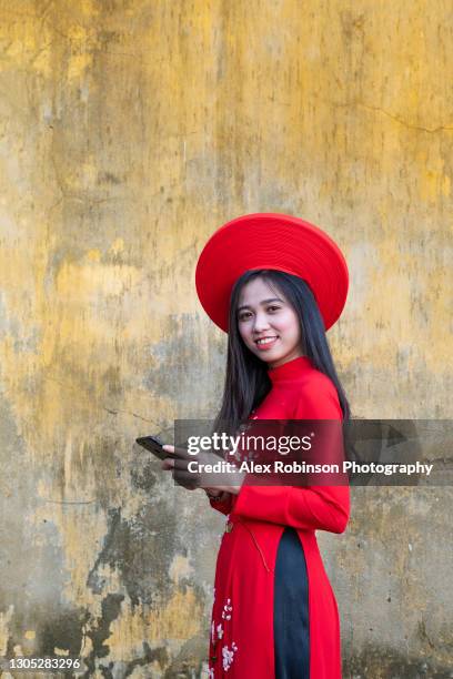 asian woman using a mobile phone in a traditional red dress and hat - korean tradition stock pictures, royalty-free photos & images