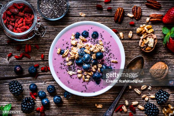 mixed berries smoothie bowl on rustic wooden table. - breakfast ingredients stock pictures, royalty-free photos & images