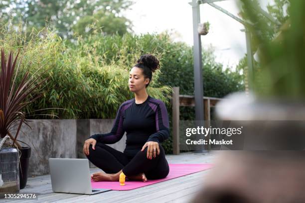 woman learning yoga from online tutorial through laptop at back yard during covid-19 - backyard deck stock pictures, royalty-free photos & images