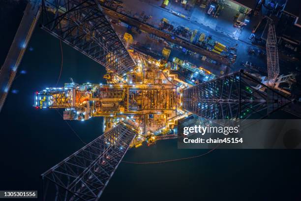 world at work drone view of oil and gas jack-up rig at the yard for maintenance with many vessels, the petroleum rig is applied for producing oil and gas in offshore in the petroleum industry. - platform stockfoto's en -beelden