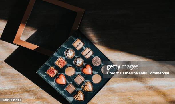 a luxurious box of chocolates illuminated by light, with space for copy. - box chocolates stock pictures, royalty-free photos & images