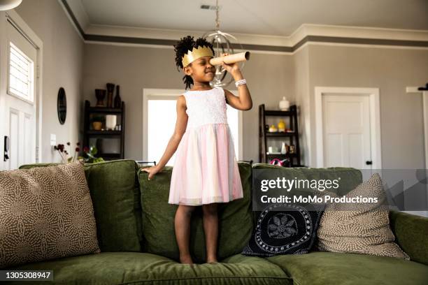 young girl wearing homemade crown and looking through homemade telescope - princesse photos et images de collection