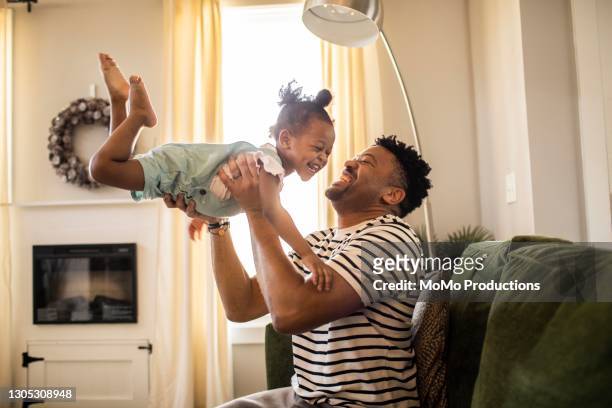 father lifting toddler daughter in the air - monoparental fotografías e imágenes de stock