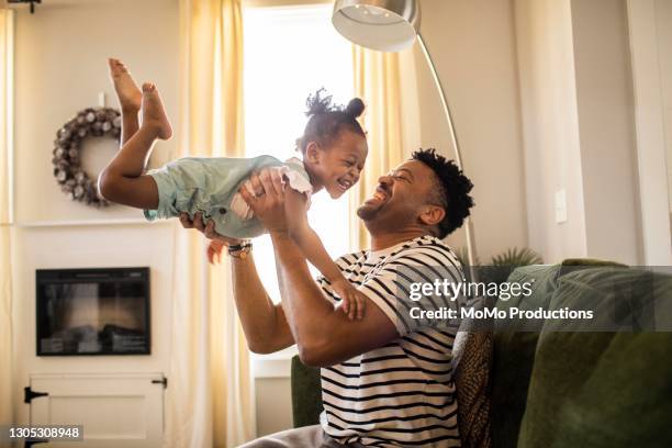 father lifting toddler daughter in the air - happy kids ストックフォトと画像