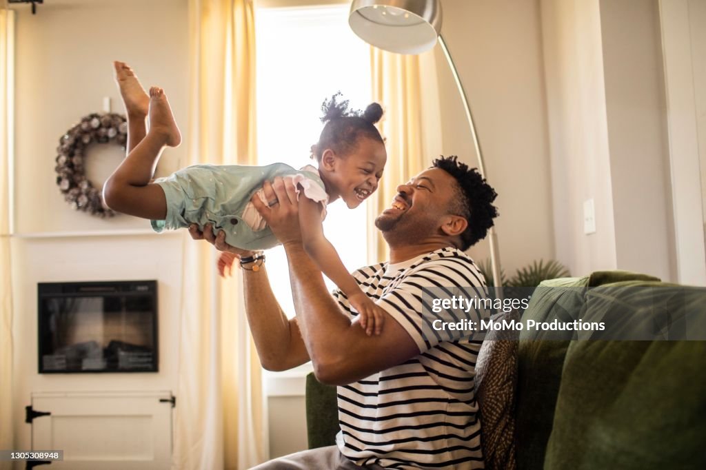 Father lifting toddler daughter in the air