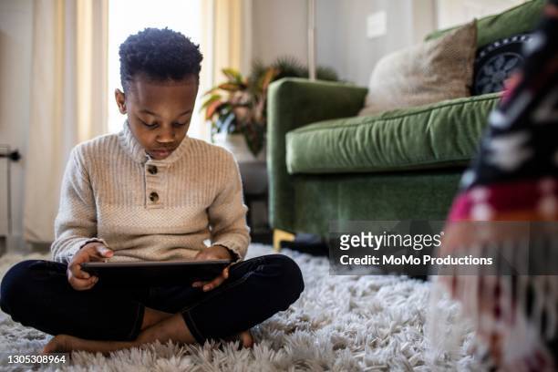 young boy watching digital tablet at home - kids ipad stock-fotos und bilder
