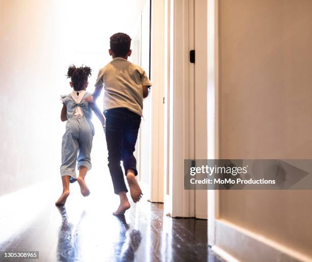 brother and sister running down hallway at home - running indoors stock pictures, royalty-free photos & images