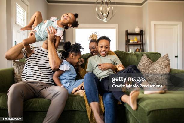 family of five playing on sofa at home - naughty daughter stock-fotos und bilder