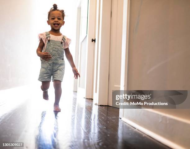 toddler girl running down hallway at home - girls wrestling stockfoto's en -beelden