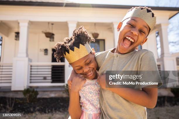 brother and sister playing outside and wearing homemade crowns - immobilie humor stock-fotos und bilder