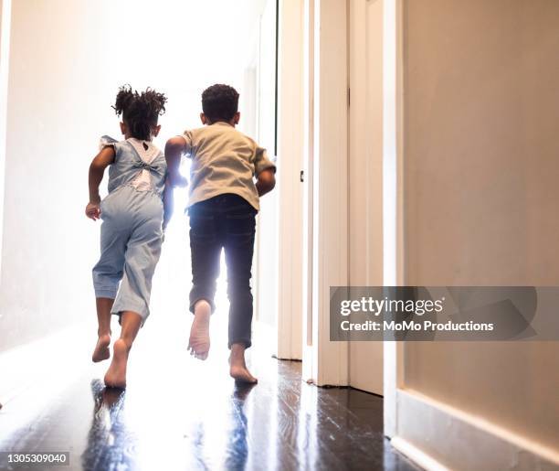 brother and sister running down hallway at home - running indoors stock pictures, royalty-free photos & images