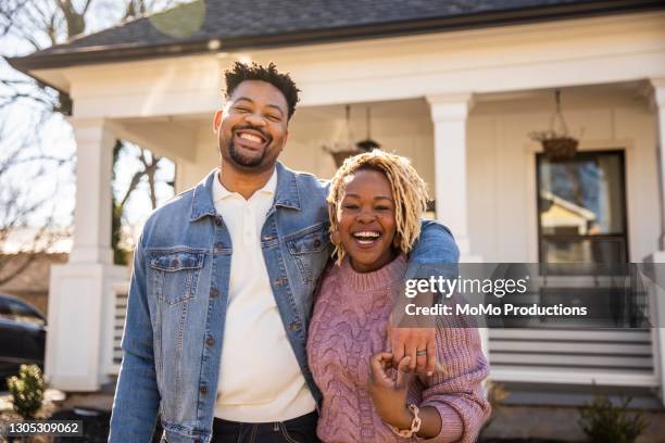 portrait of husband and wife embracing in front of home - homeowner stockfoto's en -beelden