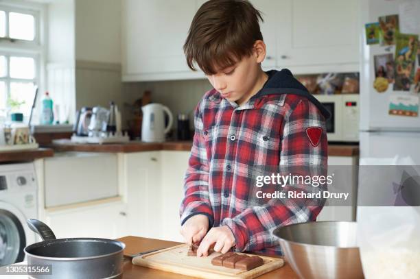 a young boy chopping chocolate bars to make a cake - boy cooking stock pictures, royalty-free photos & images