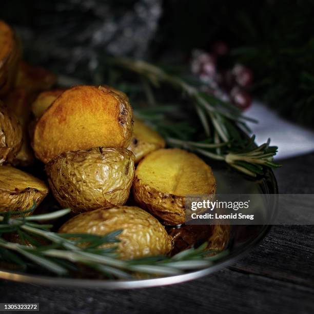 food photography of festive dish oven baked (roasted) baby potatoes with garlic and spicy herbs side view on dark blurred background close up, macro photography. - baked potato stock pictures, royalty-free photos & images