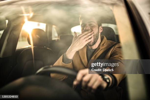 tired man driving a car and yawning. - tired driver stock pictures, royalty-free photos & images