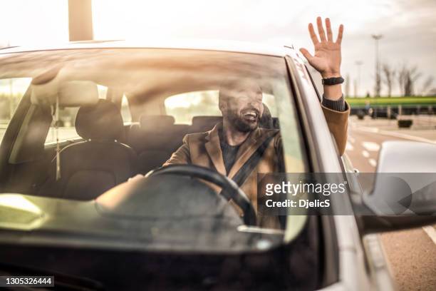 felice uomo adulto medio che guida e saluta. - sventolare la mano foto e immagini stock