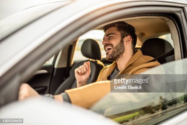 felice uomo adulto medio alla guida di una macchina e cantando. - automobile foto e immagini stock