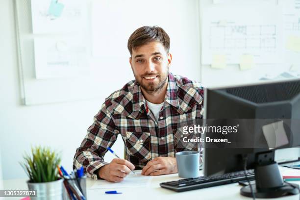 entrepreneur filling out tax return form and looking at camera - plaid shirt stock pictures, royalty-free photos & images