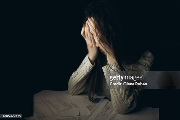young woman sits at a table in front of papers, covering her face with her hands - hand covering face stock pictures, royalty-free photos & images