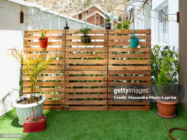 garden with wooden pallets and a few pots hanging on a sunny day - plank meubels photos et images de collection