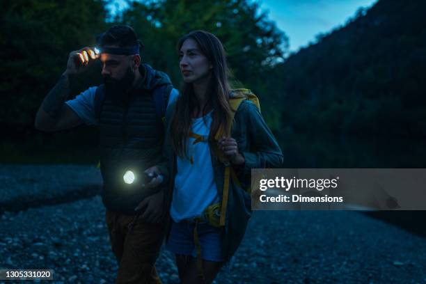 two hikers walking with flashlights - dark forest night stock pictures, royalty-free photos & images
