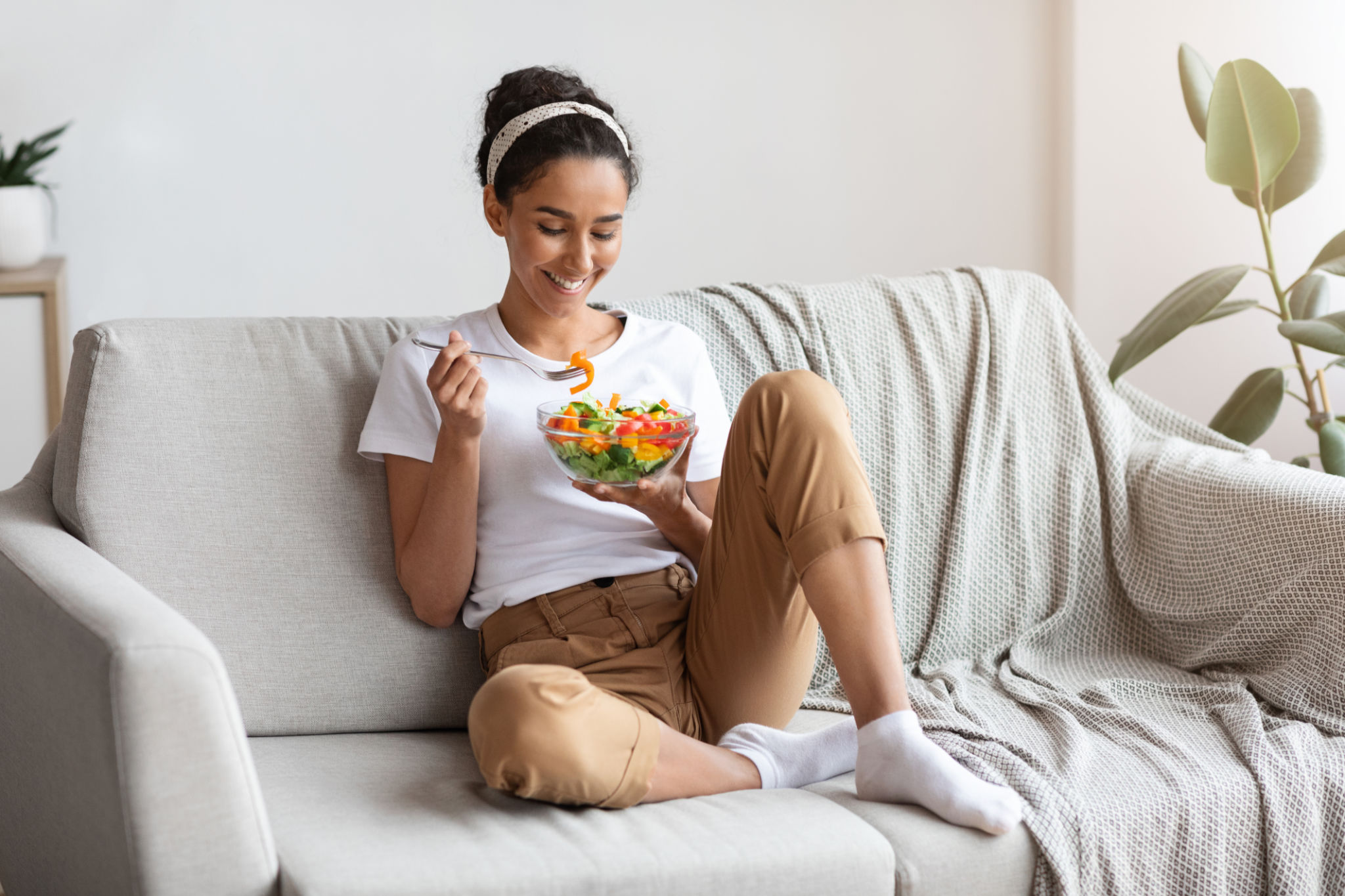 Young and beautiful lady sitting on couch, eating salad Young and beautiful lady sitting on couch, eating salad