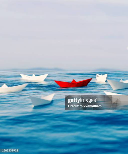 red paper ship sails around other boats on the sea - toy sailboat stock pictures, royalty-free photos & images