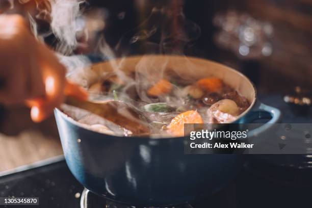 steaming stew in blue cast iron pot on stove - kochlöffel stock-fotos und bilder