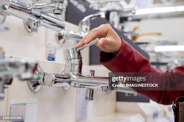 woman looking at faucets in plumbing showroom - plumbing products stock pictures, royalty-free photos & images
