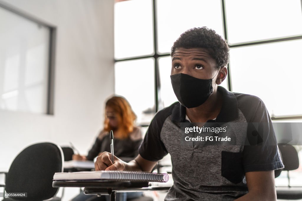 Student taking notes or taking a test at school - wearing face mask