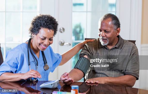 home health aide checking patient's blood pressure - 55 to 60 years old african american male stock pictures, royalty-free photos & images