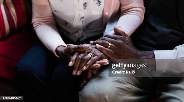 senior african-american couple sitting, holding hands - old couple holding hands stock pictures, royalty-free photos & images