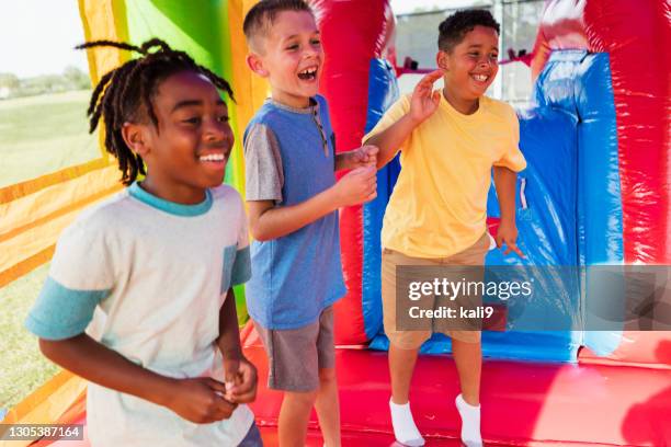 multiethnische jungen spielen in bounce house - inflatable playground stock-fotos und bilder